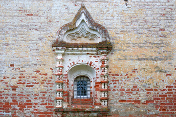 A beautiful window in a niche of an old brick wall. The window is decorated with stucco and a beautiful arched vault.