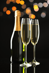 Flute glasses with sparkling wine and bottle on black background. Merry Christmas and Happy New Year