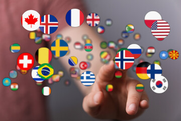 Close-up shot of a hand reaching towards a cluster of international flags, symbolizing global unity, travel and diverse cultures. Ideal for illu