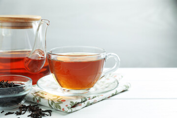 Hot tea in cup and teapot on white wooden table. Space for text