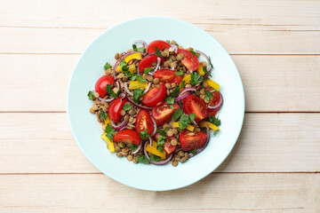 Delicious salad with lentils and vegetables on light wooden table, top view