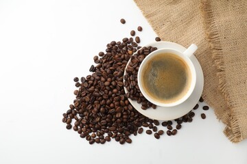 Cup of aromatic coffee and roasted beans on white background, flat lay