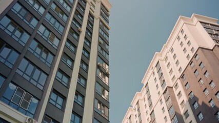 Looking Up At Glass Skyscraper Towers With Clear Blue Sky, Modern Brick And Concrete Facades, Reflective Windows, Sharp Vertical Lines And Warm Sunlight, Calm Urban Ambience Ideal For Architecture,