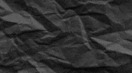 Halftone crumpled paper texture with wite a dotted, rough, and wrinkled surface. Black creased sheet background in comic pop-art style, featuring grainy folds and gritty distressed details. © Maryna