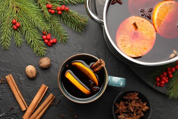 Mug with tasty mulled wine and ingredients on black table, flat lay