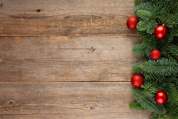 Evergreen frame of fir branches with red christmas balls and red ribbon. Christmas background. Shot from above.