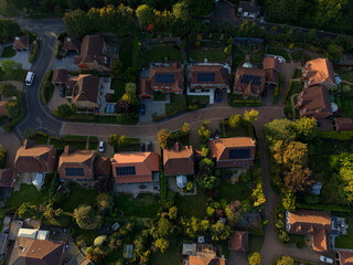 Aerial view of rooftops and solar panels at sunset. Quiet residential street with houses and gardens. Safe communal sustainable living in UK. Modern houses for young families. Aerial top down view. © Ssisabal