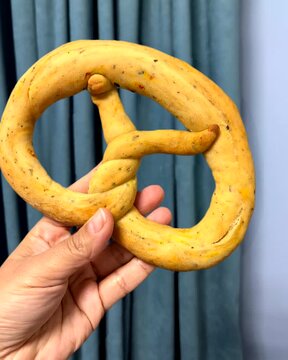 hand holding  a baked kalach, a pretzel