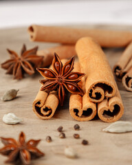 Warm spices arrangement featuring cinnamon sticks, star anise, and cardamom pods on a rustic wooden surface.