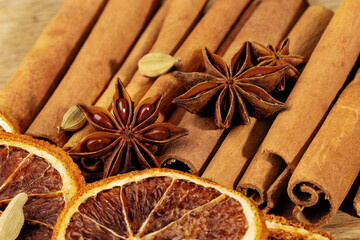  Horizontal close-up of a bright festive arrangement with numerous cinnamon sticks and star anise pods framed by dried orange slices