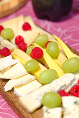 Appetizer of different kinds of cheeses with grapes and raspberries