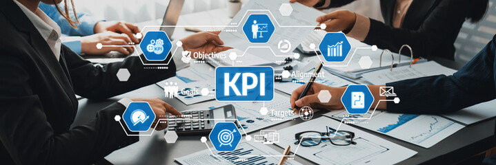 A group of business professionals engaged in discussion and analysis of Key Performance Indicators (KPI) with visual aids, highlighting collaboration and strategy in a dynamic office. Amity