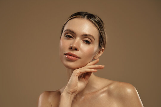Close-up of young woman with glowing skin touching her chin