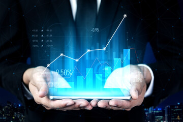 A business professional holds a digital tablet displaying a vibrant graph that represents financial growth and success, set against a modern urban backdrop at night. Scalp