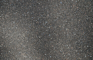 Texture of dark, grainy asphalt with uneven texture. Rough, abstract background.