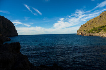 Scenic Mediterranean coastal landscape with dramatic cliffs, green pine forest and deep blue sea under a clear sky