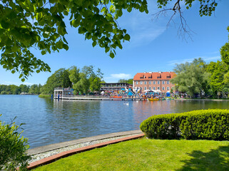 Serene lake scene with lush greenery and vibrant buildings, Szczecinek, Poland
