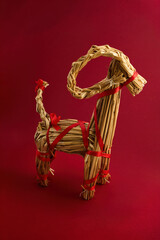 Straw Goat Sculpture. A straw goat sculpture with red ribbons against a red backdrop.