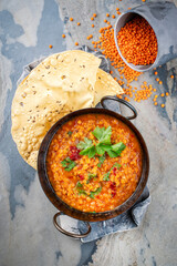 Indian Dal fry red lentils with chili papadam servied as top view in iron pot 