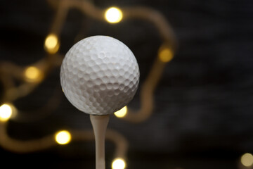 Golf used ball on a tee on a black background close-up