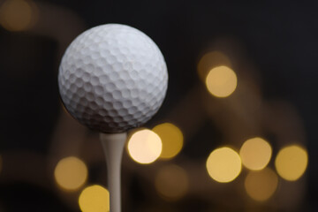 Golf used ball on a tee on a black background close-up