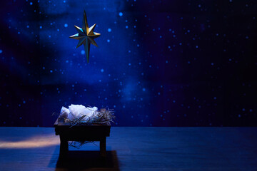 Obraz premium Starry Night Nativity. A nativity scene under a glowing star in a deep blue, starry background