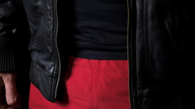The man unzips his leather jacket. Metal zipper. A man in outerwear. Biker or punk style. Casual clothes. High quality 4k footage.