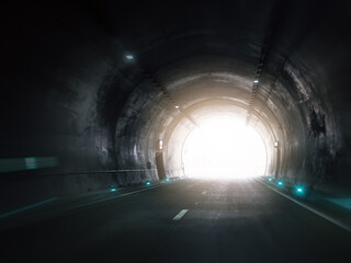 Light at end of dark highway tunnel with glowing exit. Hope, direction, breakthrough and progress, modern transportation and motivational concept.