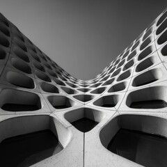 Upward View of Futuristic Concrete Honeycomb Facade with Organic Window Openings and Symmetric Curves. AI generative