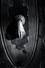 Vintage door knocker shaped as a hand on a wooden door. Classic architectural detail with historic character.