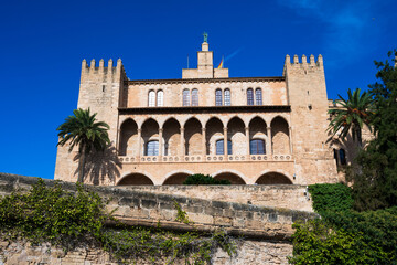 Historic fortified palace with arches and towers under a deep blue sky. Iconic Mediterranean landmark and heritage architecture.