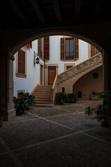 Narrow Mediterranean old town street with stone buildings, plants and cobblestone pavement.