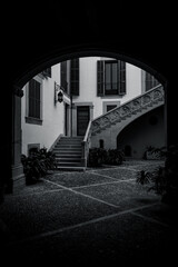 Narrow Mediterranean old town street with stone buildings, plants and cobblestone pavement.