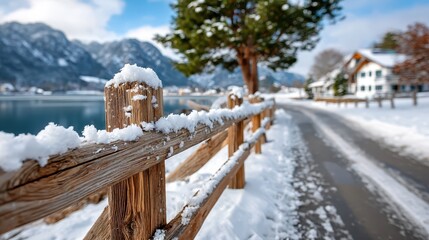 A serene winter landscape showcases a snow-covered wooden fence beside a frozen lake, surrounded by trees and mountains, conveying a sense of calmness and natural beauty in winter.