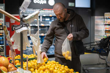 Man shopping for oranges in a grocery store during the daytime