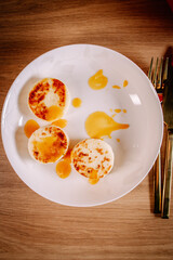 Top view of cheese pancakes with fruit sauce on white plate. Homemade sweet breakfast or dessert with clean minimal composition.