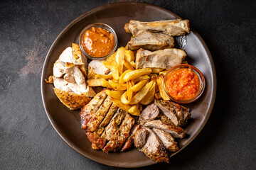 Grilled meat platter with fries and sauces