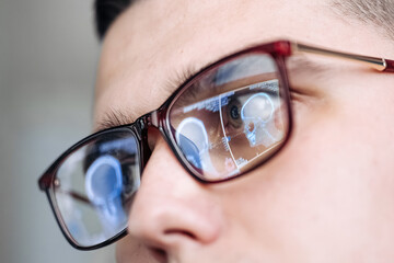 Fototapeta premium Close-up of a male healthcare professional wearing glasses, reflecting medical imaging technology, showcasing advanced oncology treatment concepts in a clinical environment