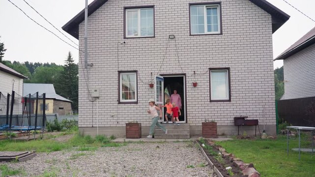 Female Adult Takes Children To Outdoors, Mother Leads Youngsters Down Stairs Into Bright Yard, Woman And Children Step Outside Through Brick Entrance Into Lively Suburban Morning Scene