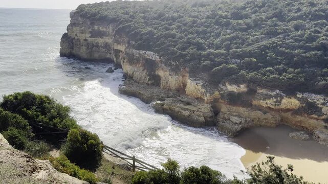 Aerial seascape and coastline cliffs of Praia do Barranco das Belharucas beach, in Algarve region in South Portugal. Praia do Barranco das Belharucas beach, Albufeira, Algarve, Portugal.