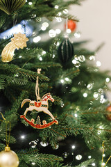 Horse christmas toy hanging on tree branch with festive lights. Symbol 2026. Happy New Year and Happy Holidays! ! Copy space.Stylish vintage ornament