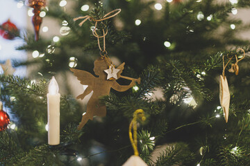 Obraz premium VIntage christmas angel toy hanging on xmas tree branch with festive lights. Happy New Year and Happy Holidays! ! Copy space. Stylish ornament