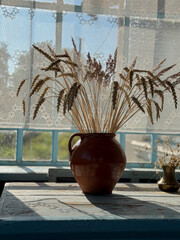 Dried wheat stalks and pampas grass in clay jug