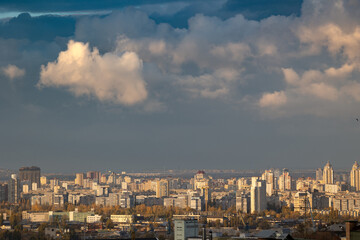 Obraz premium Sunlit cumulus clouds over dense urban cityscape view