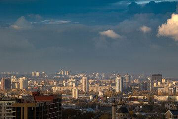 Fototapeta premium Sunlit cumulus clouds over dense urban cityscape view
