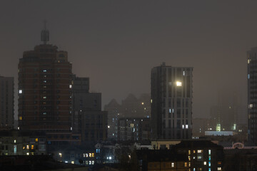 Fototapeta premium Tall round brick residential tower in night cityscape