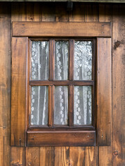 Rustic cabin window featuring white lace curtain