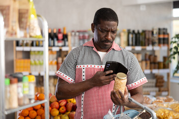 Fototapeta premium Adult male shopper scanning qr code for beans in jar in grocery store