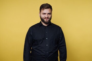 Obraz premium Man smiles against yellow background while wearing black shirt and standing with neutral pose in studio setting