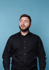 Obraz premium Man stands against blue wall looking up with interest in studio setting during daytime
